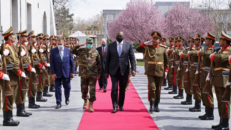 U.S. Defense Secretary Lloyd Austin, center, walks on the red carpet with Acting Afghan...