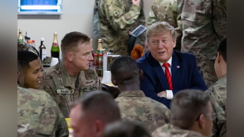 President Donald Trump speaks with members of the military during a surprise Thanksgiving Day...
