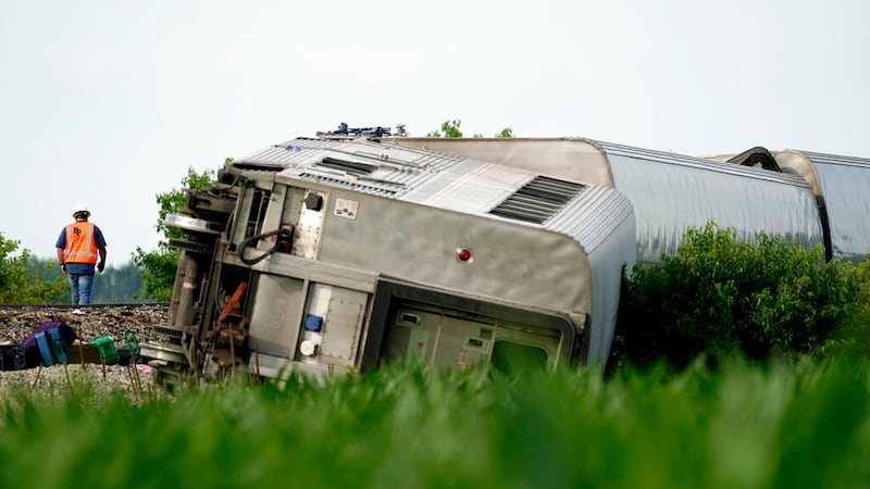 A worker inspects the scene of an Amtrak train which derailed after striking a dump truck,...