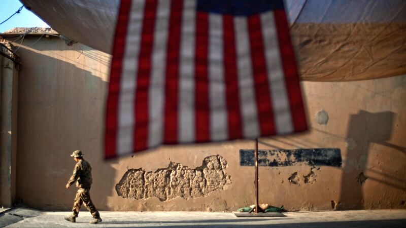 In this Sept. 11, 2011 file photo, a U.S. Army soldier walks past an American Flag hanging in...