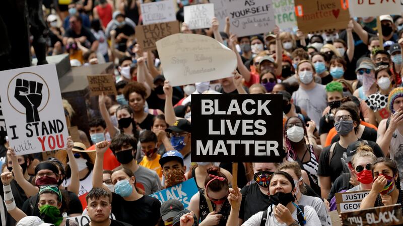 FILE - In this June 5, 2020, file photo, people hold signs as they listen to a speaker in...